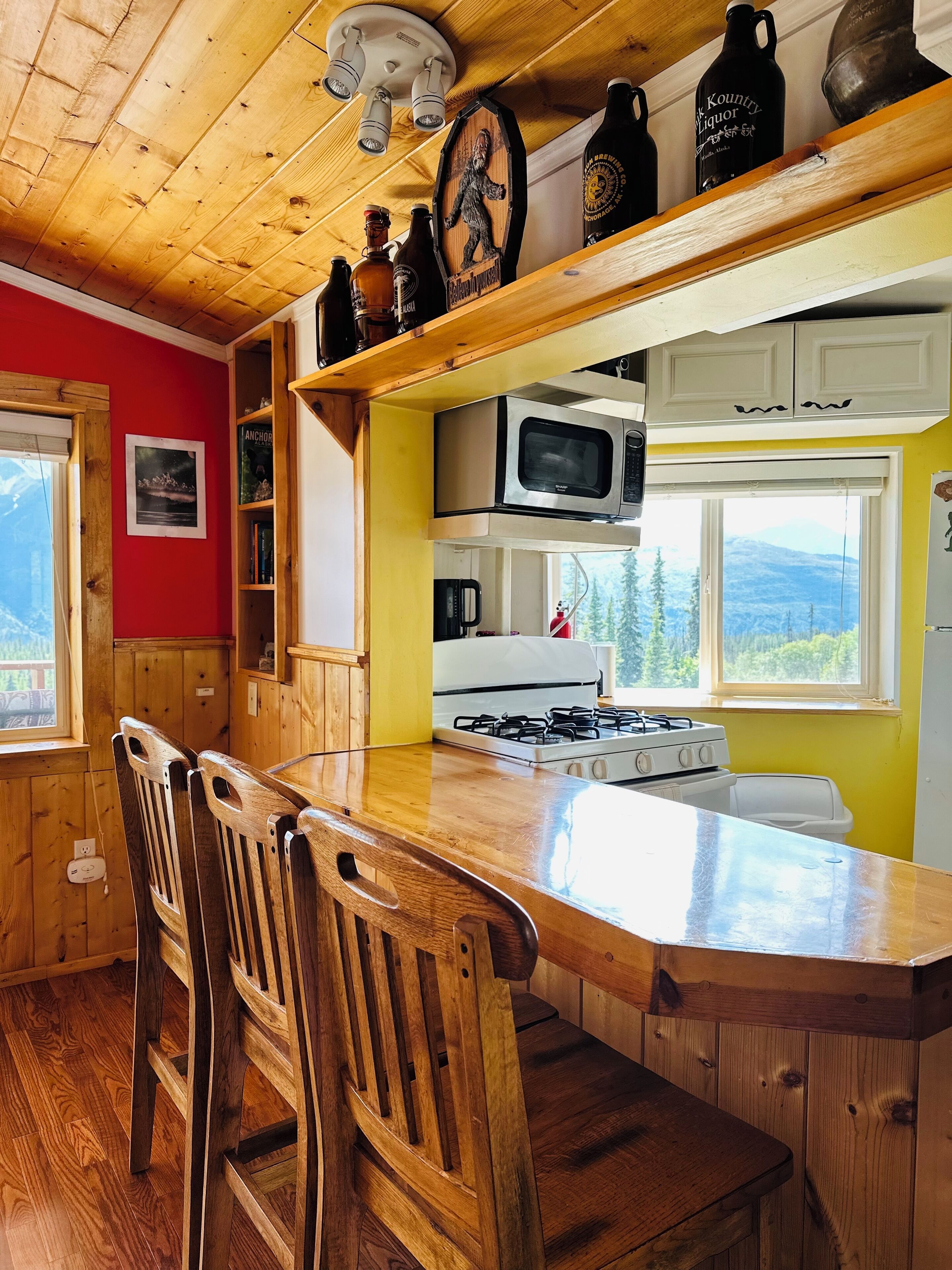 Une cuisine avec des meubles en bois, un four à micro-ondes, une cuisinière et un grand îlot central doté de chaises.