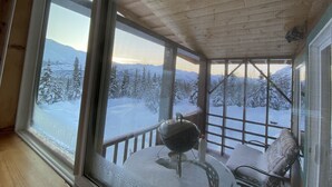 A room with a large window overlooking a snowy mountain landscape.