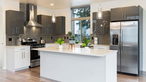 A modern kitchen with a large island, stainless steel appliances, and pendant lighting. - Luxe 3Bdr Home | Parking | Roof Oasis | City Views (Seattle)