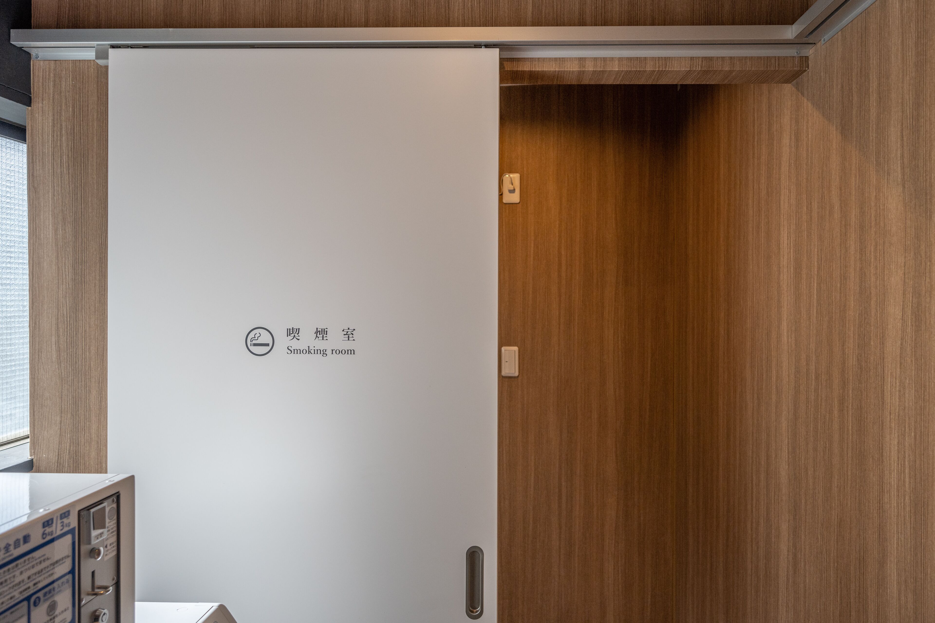 A white sliding door with a smoking room sign, indicating a designated smoking area.