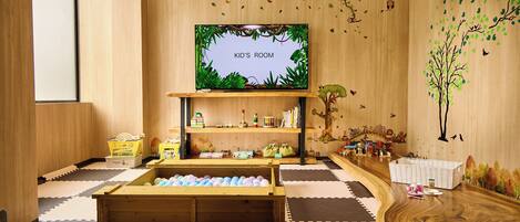 A children's room with a TV, wooden shelves, a play area, and a bookshelf.