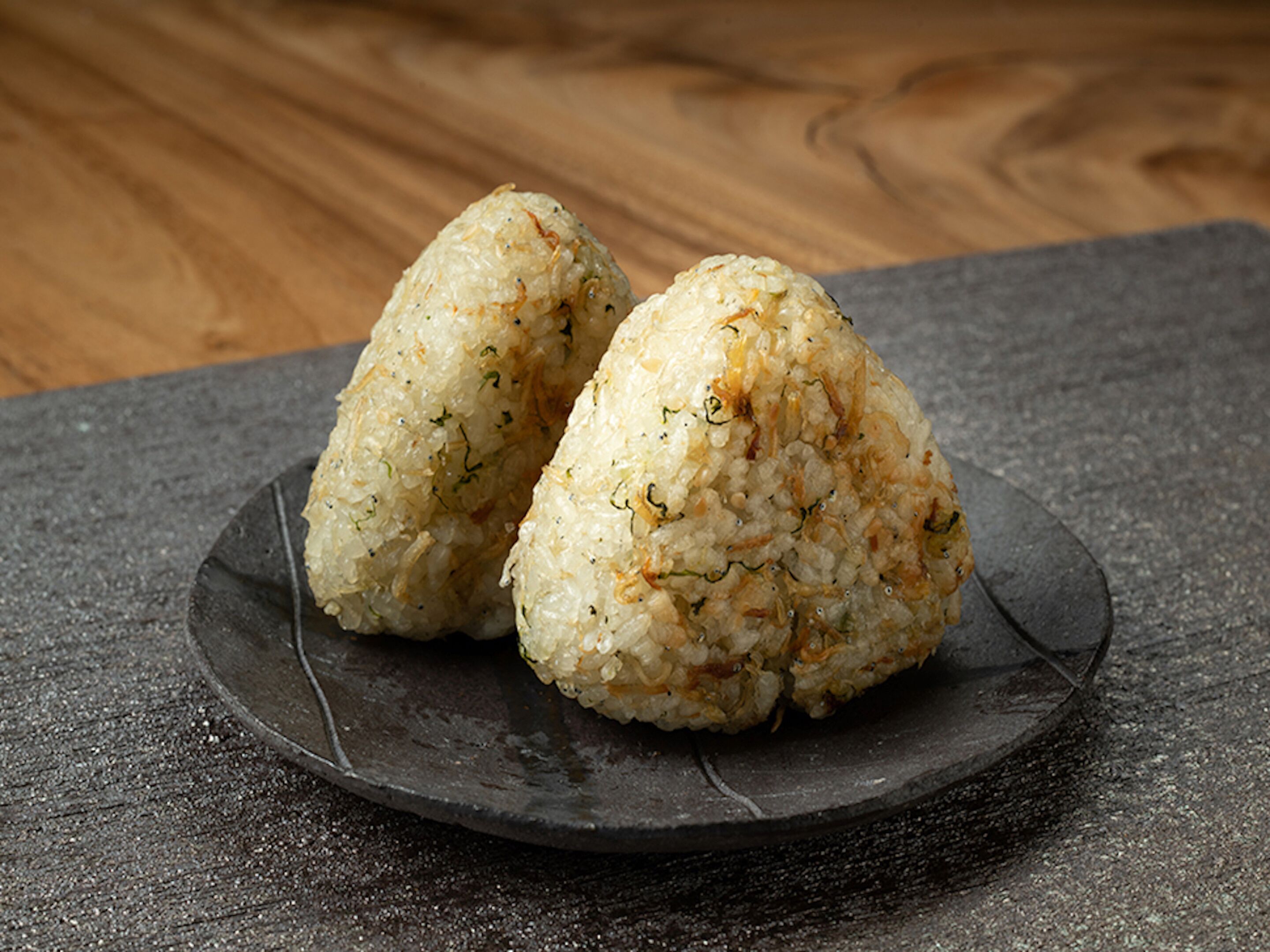 Two rice balls on a dark plate.