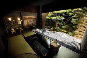 A traditional Japanese-style bathroom with a small indoor garden, a stone hot tub, and a bamboo screen. - YUMURAONSEN MIDORIYA (Shinonsen)