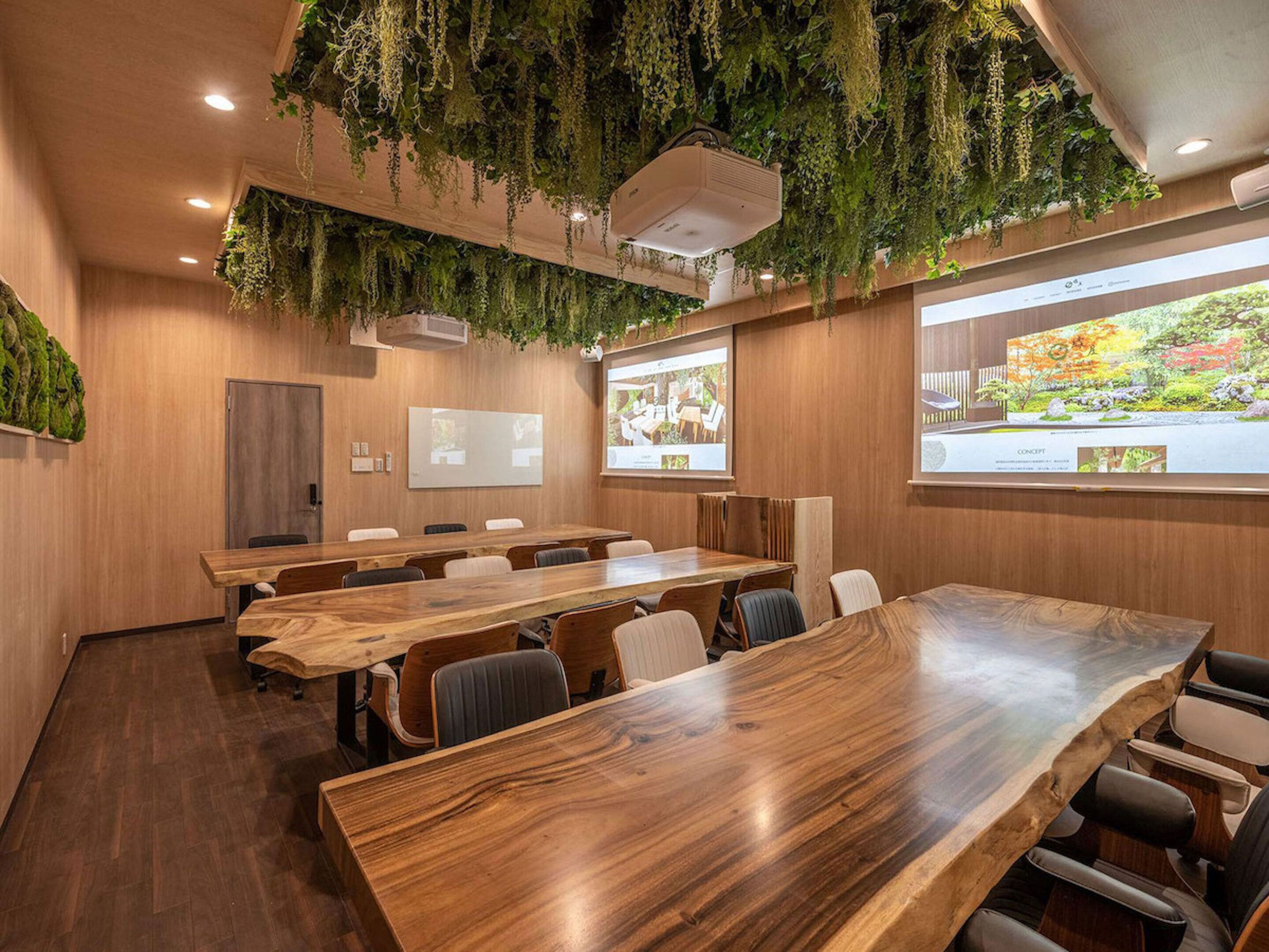 A conference room with wooden tables and chairs, a whiteboard, and a projector screen displaying a presentation.