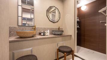 A modern bathroom with a large mirror, a bowl sink, and a shower area.