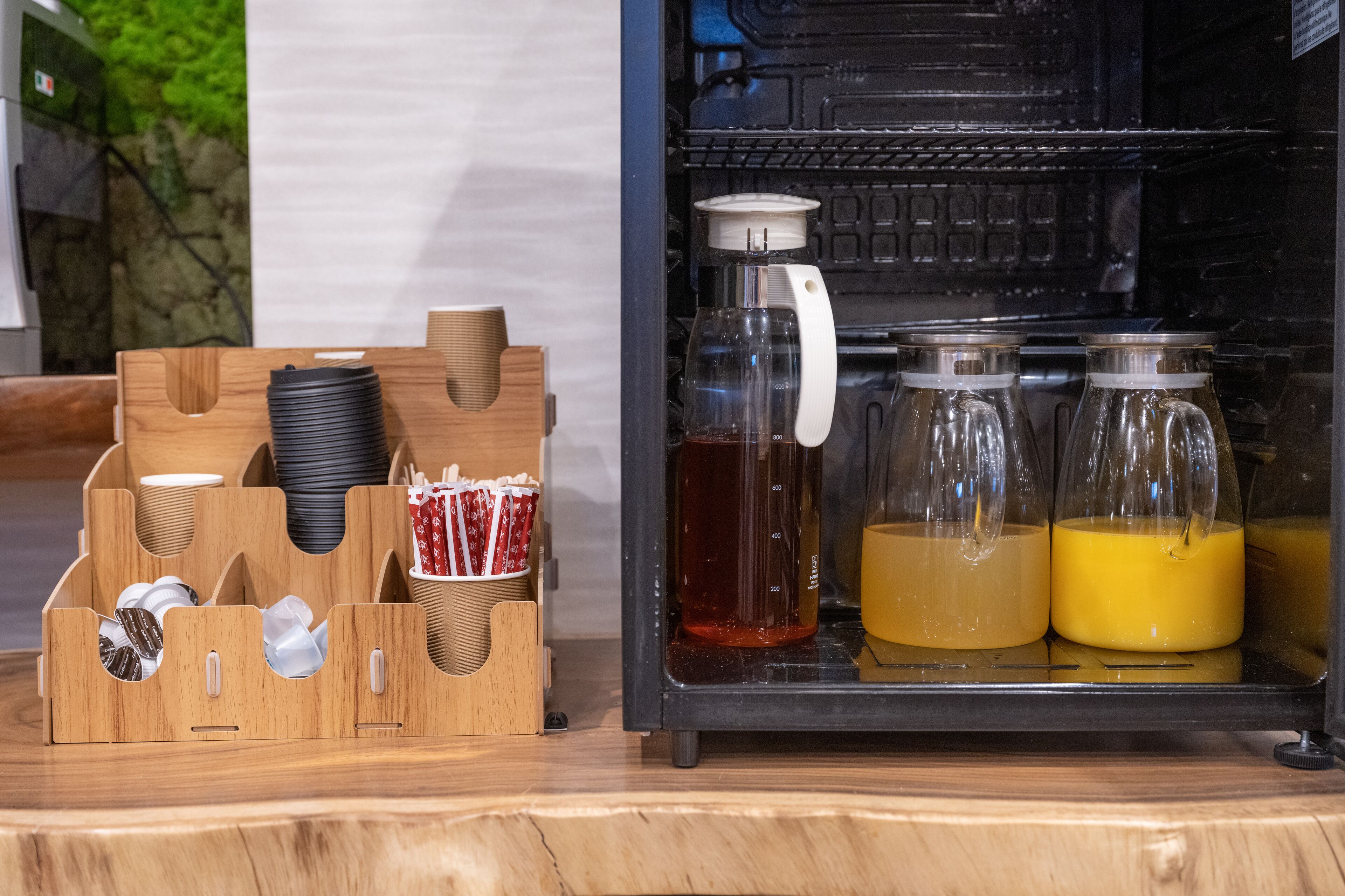 A beverage dispenser with various drink options and a stack of disposable cups.