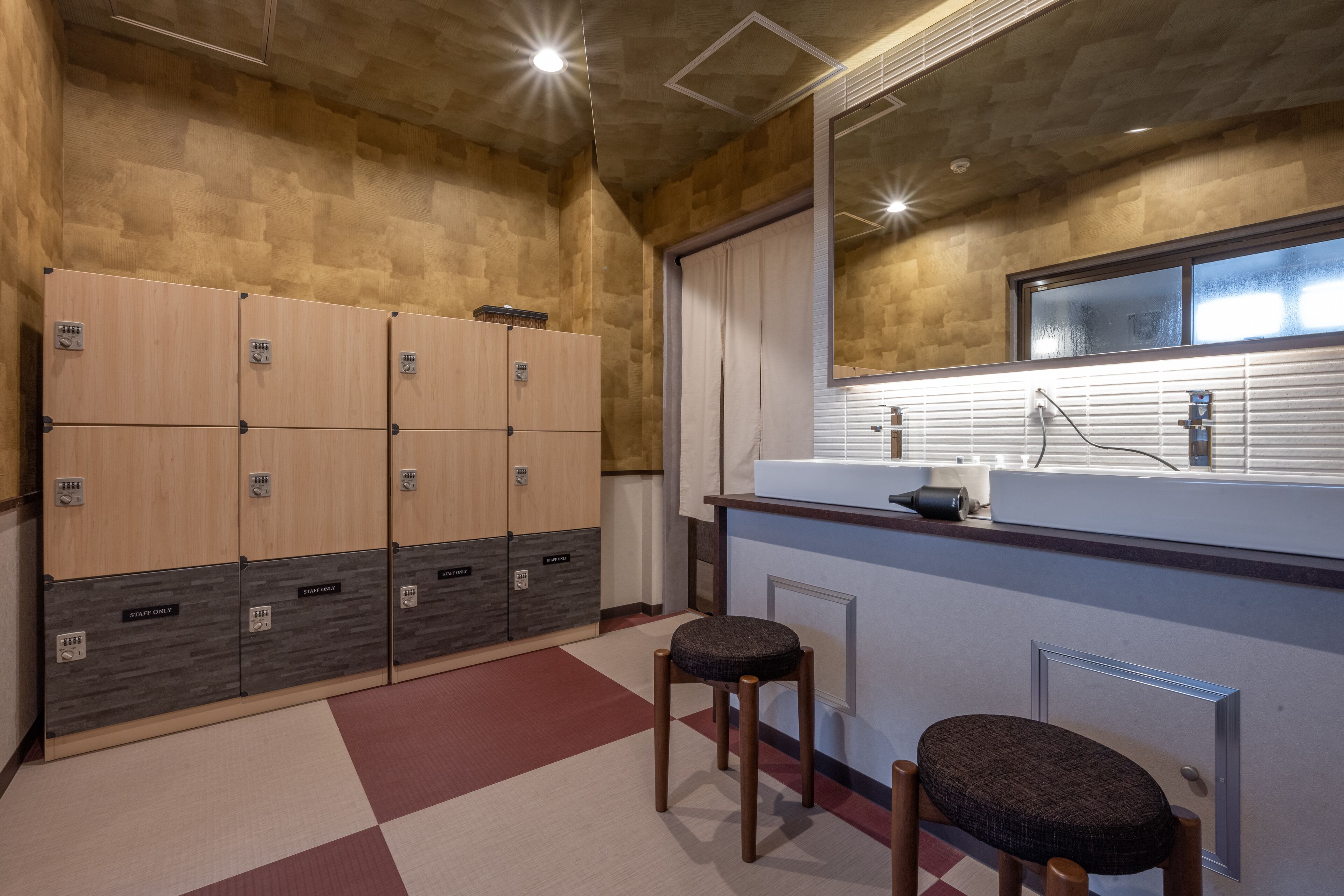 Un baño moderno con taquillas de madera, un lavabo y dos taburetes.