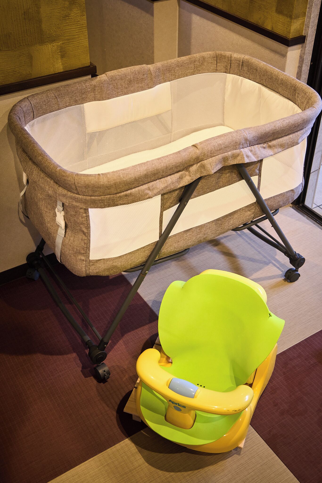 A baby bassinet with a yellow and green chair.