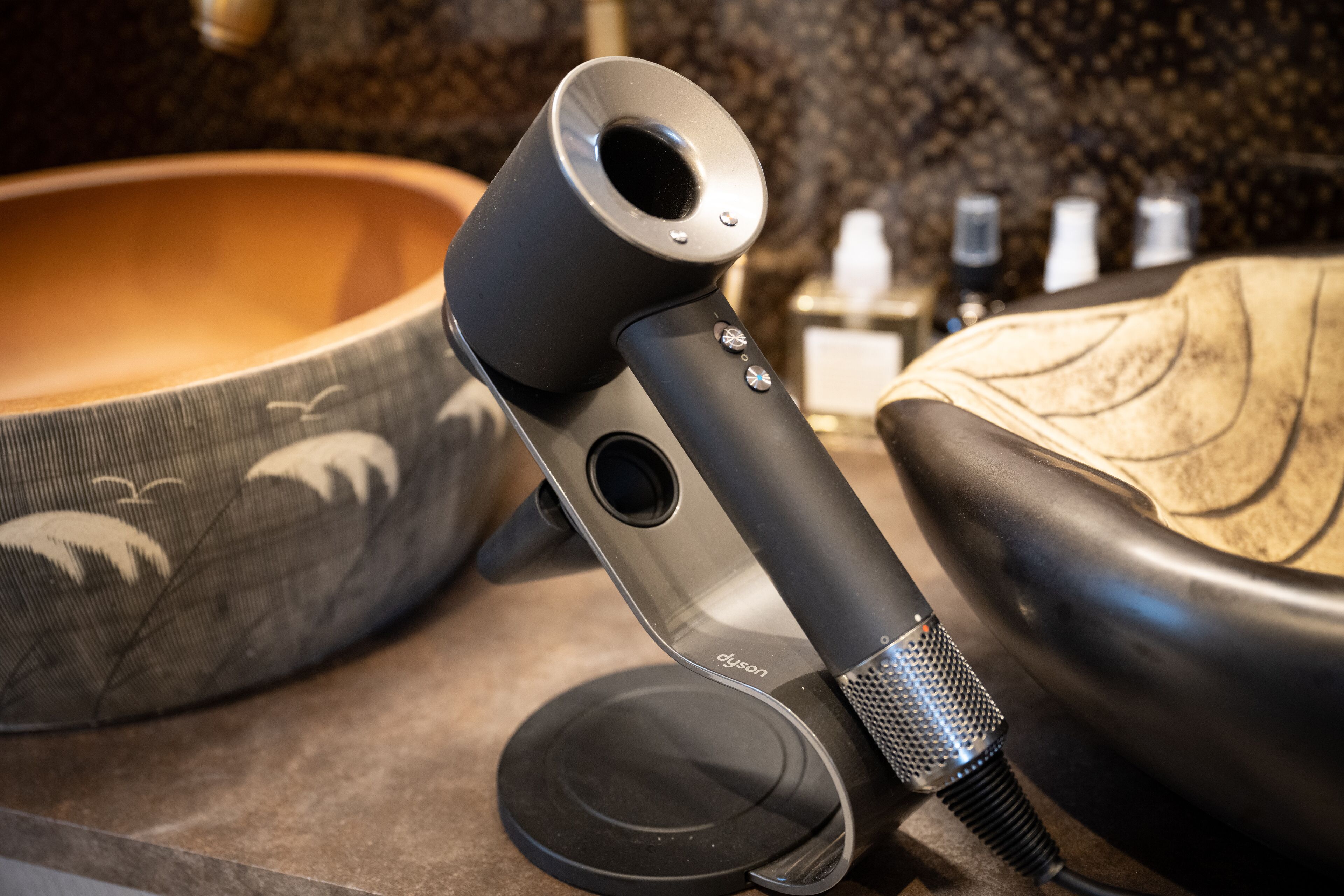 Un secador de pelo Dyson sobre una encimera, junto a un bol.