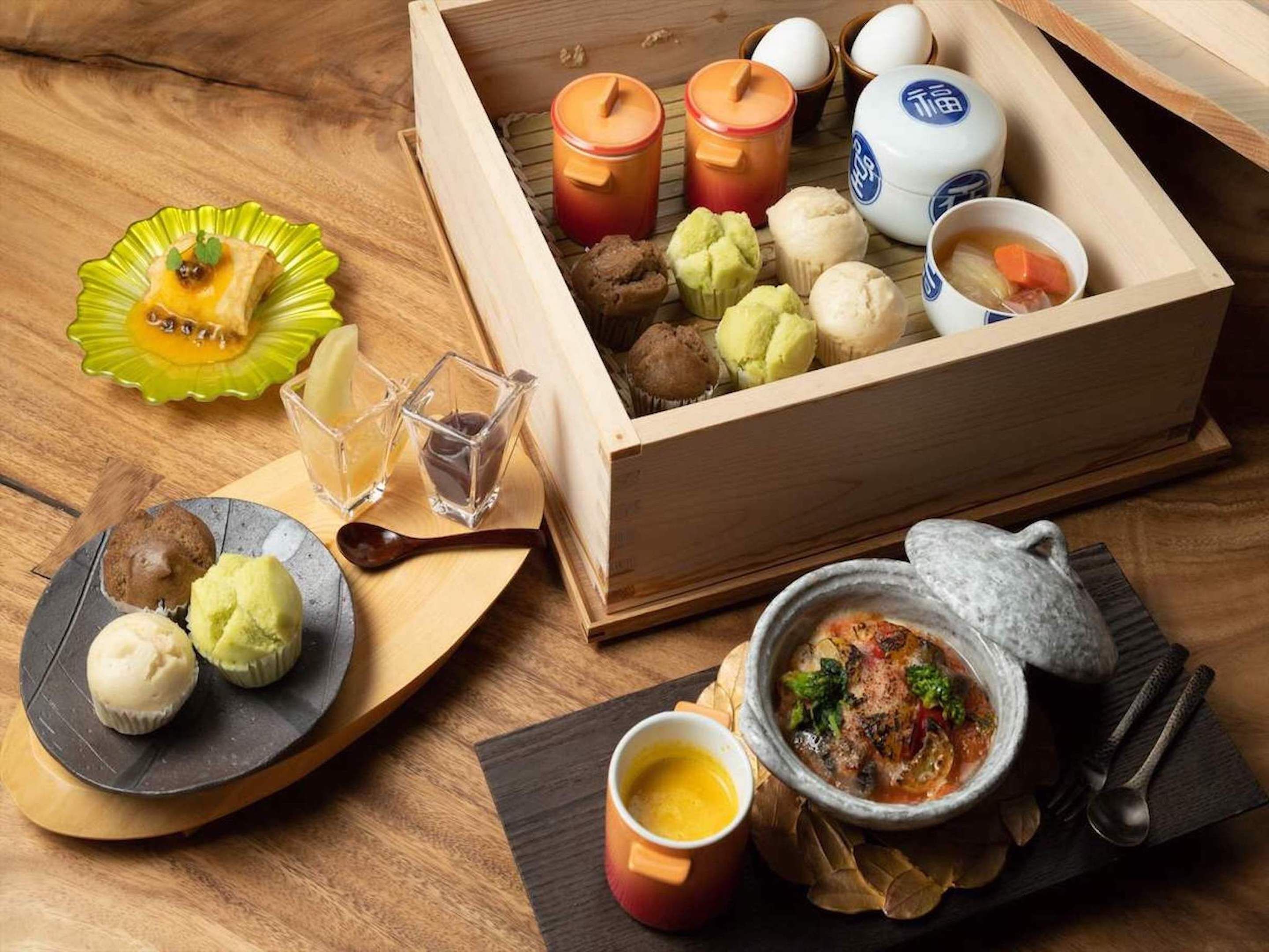 A wooden box containing various food items, a bowl of soup, and a plate with dumplings.