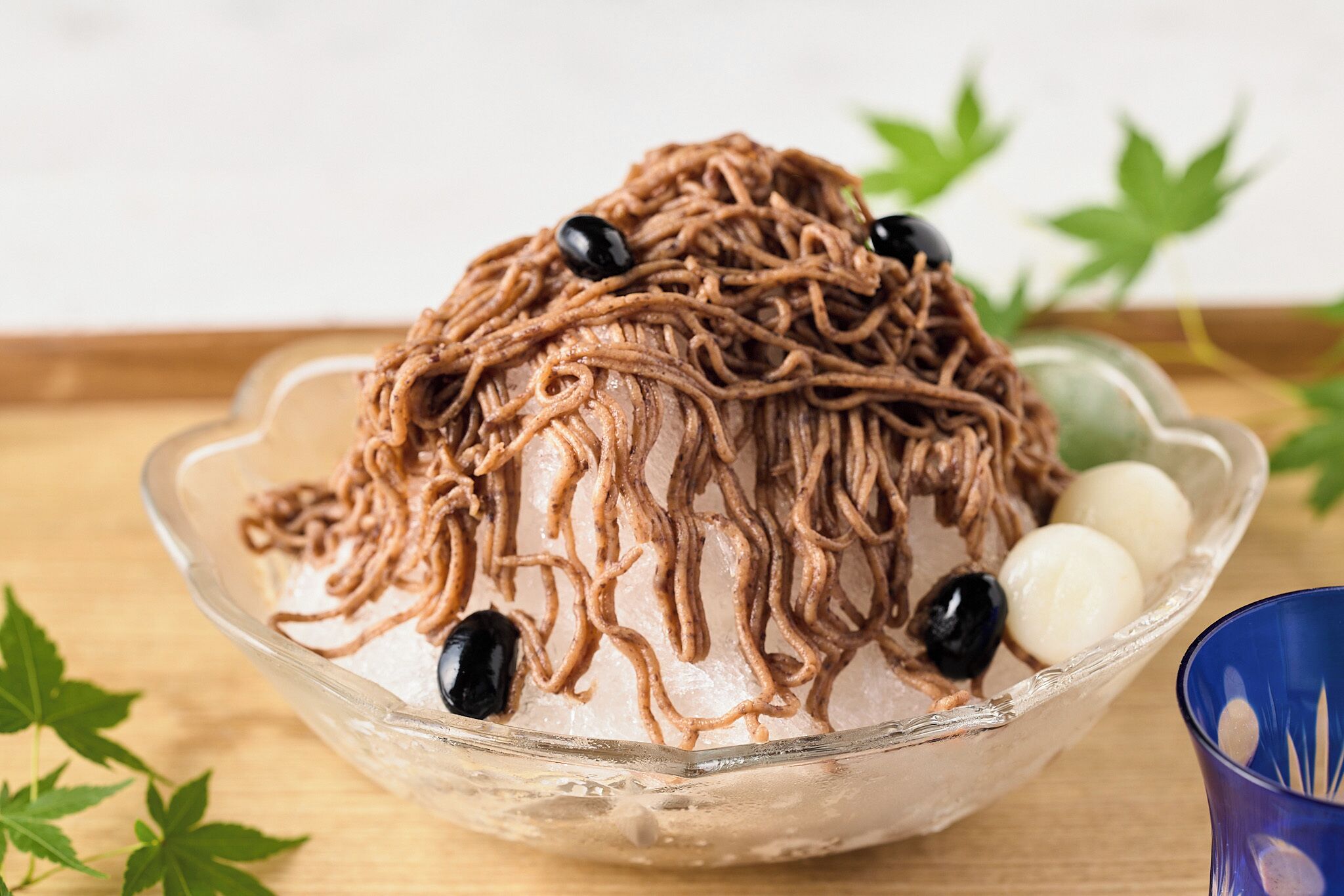 A bowl of noodles with black olives and white balls on ice.