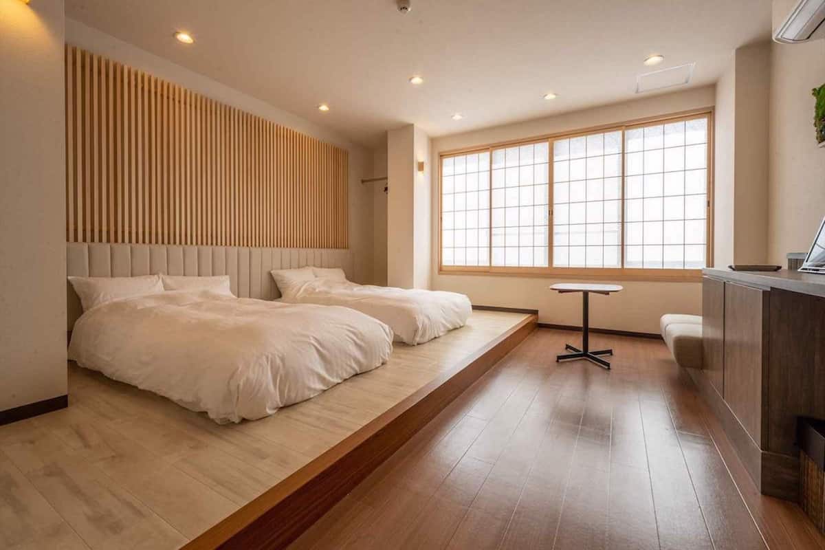 Une chambre moderne avec deux lits, une petite table et une grande fenêtre.