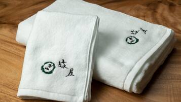 Two folded white towels with embroidered designs on a wooden floor.