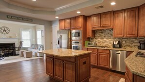 A spacious kitchen with wooden cabinets, granite countertops, and modern appliances. - 4 BR, 2.5 BA Townhome, Quick shuttle to Beach, Close to Pools, Waterpark, and Free Activities! (Ocean View)