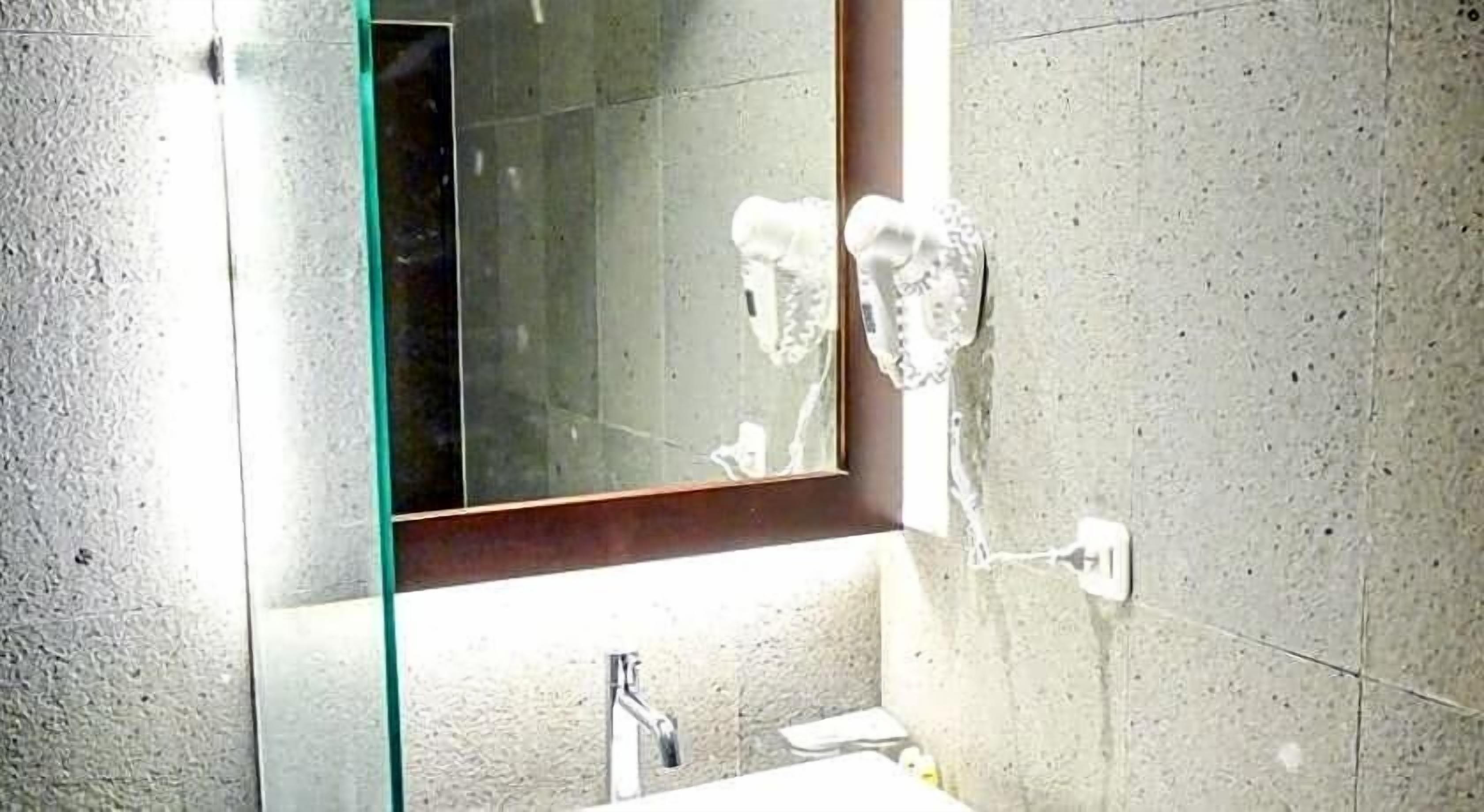 A bathroom with a glass shower enclosure, a sink, and a mirror.