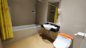 A bathroom with a bathtub, sink, and toilet. - Odaita Hotel (Pamekasan)