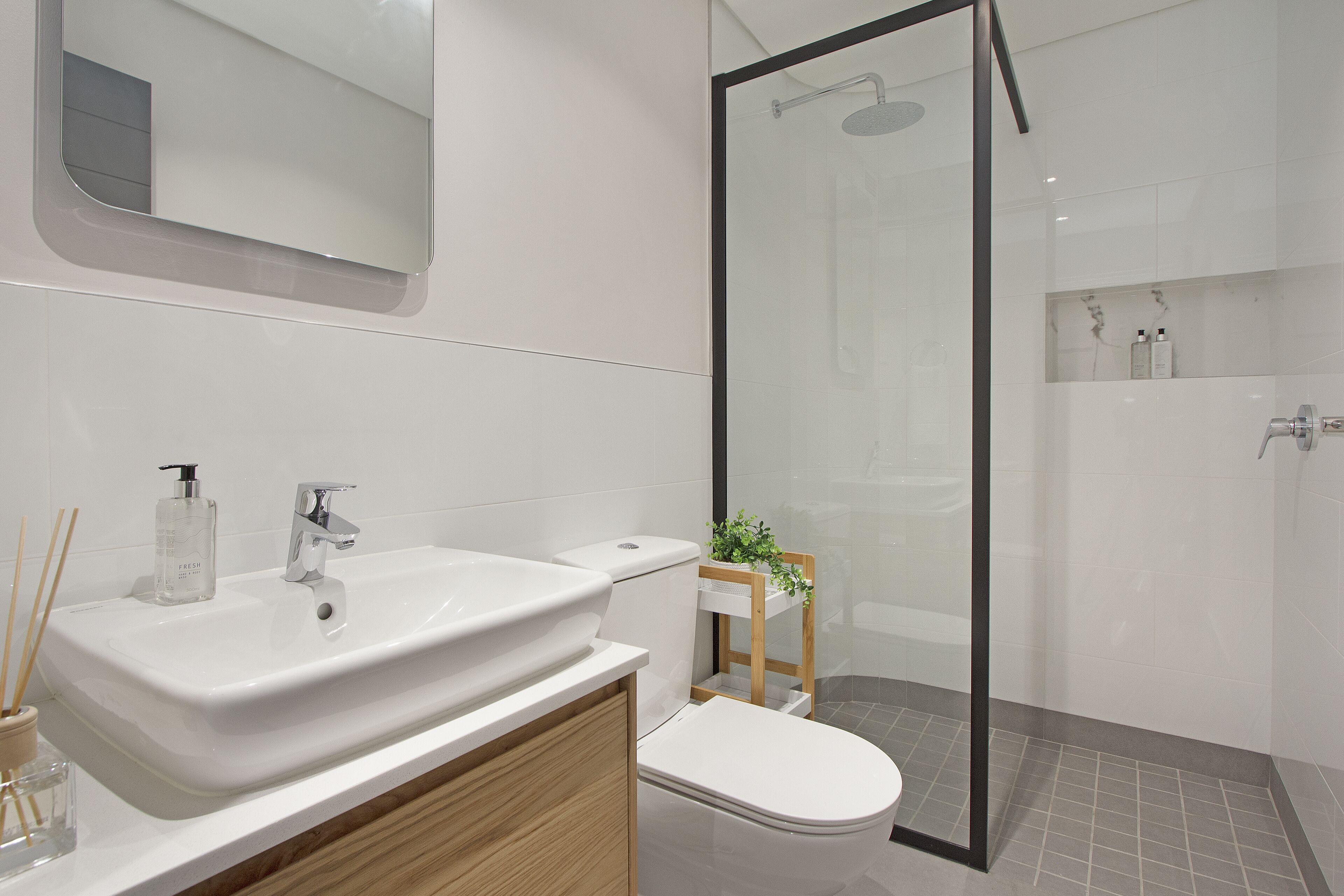 Une salle de bain moderne avec un lavabo blanc, des toilettes et une douche à parois de verre.