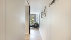 Un pasillo moderno con una zona de comedor al fondo, con un sofá y una mesa.