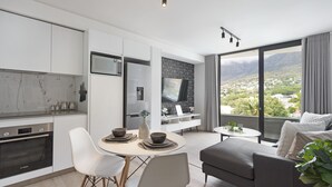 Una cocina moderna con armarios blancos, un horno Bosch y un comedor con una mesa redonda y sillas.