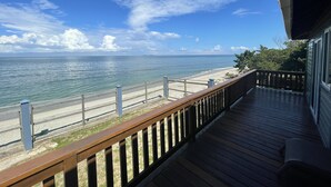 A wooden deck with a view of the beach and ocean.