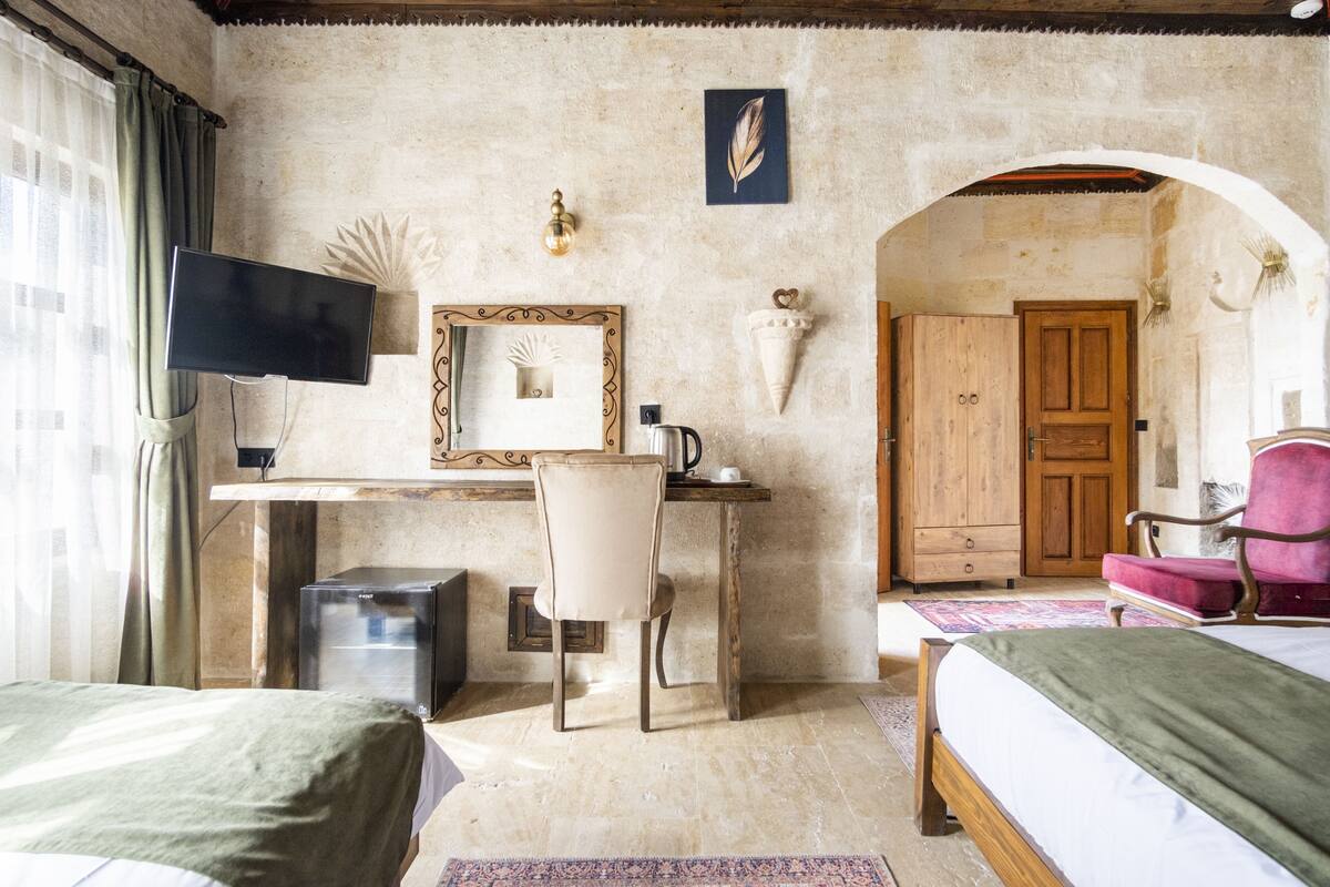 Un dormitorio con una cama, un escritorio con silla, un televisor y una puerta de madera.