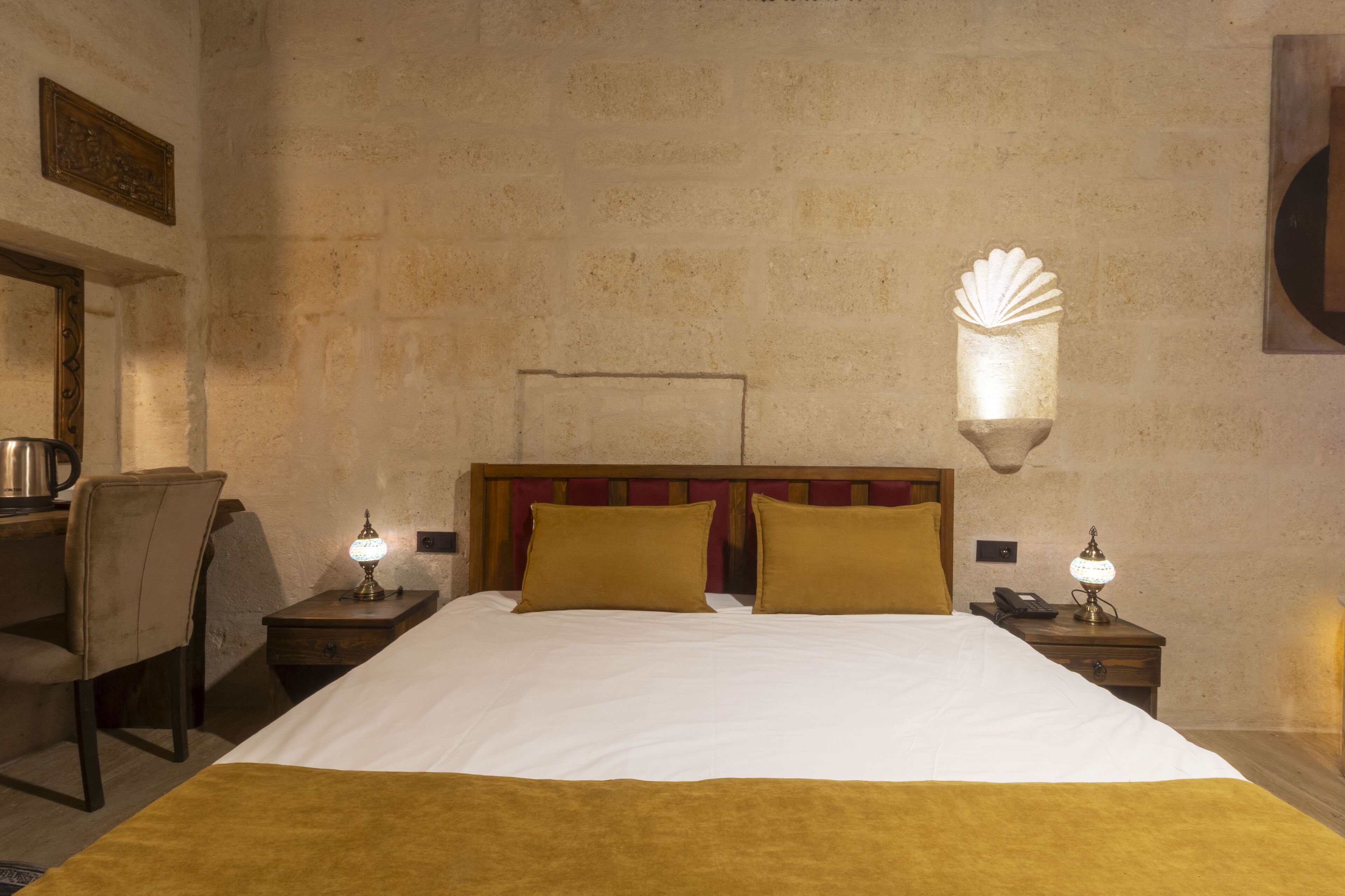 A hotel room with a large bed, two bedside tables with lamps, a chair, and a decorative wall piece.