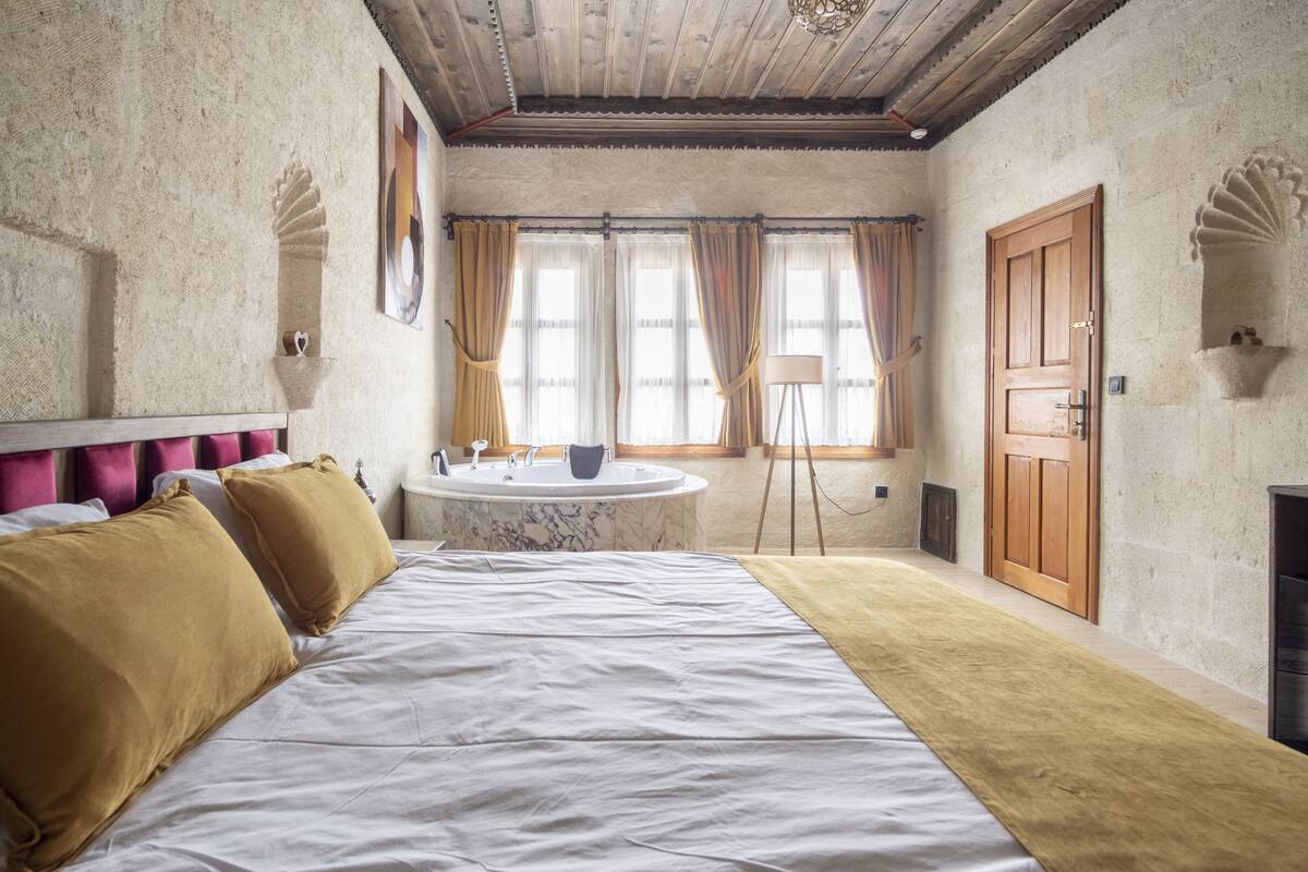 Un dormitorio con una cama grande, una bañera de mármol y una puerta de madera.