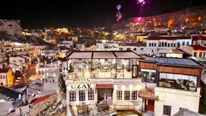 A hotel with a rooftop terrace, a visible 'UZAY CAVERN SUITE' sign, and a view of the cityscape in the background. - Uzay Cave Suite Hotel (Ürgüp)