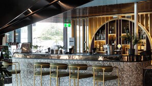 A modern bar area with a marble countertop, bar stools, and a ceiling with exposed ductwork. - Soho Hotel Auckland (Auckland)