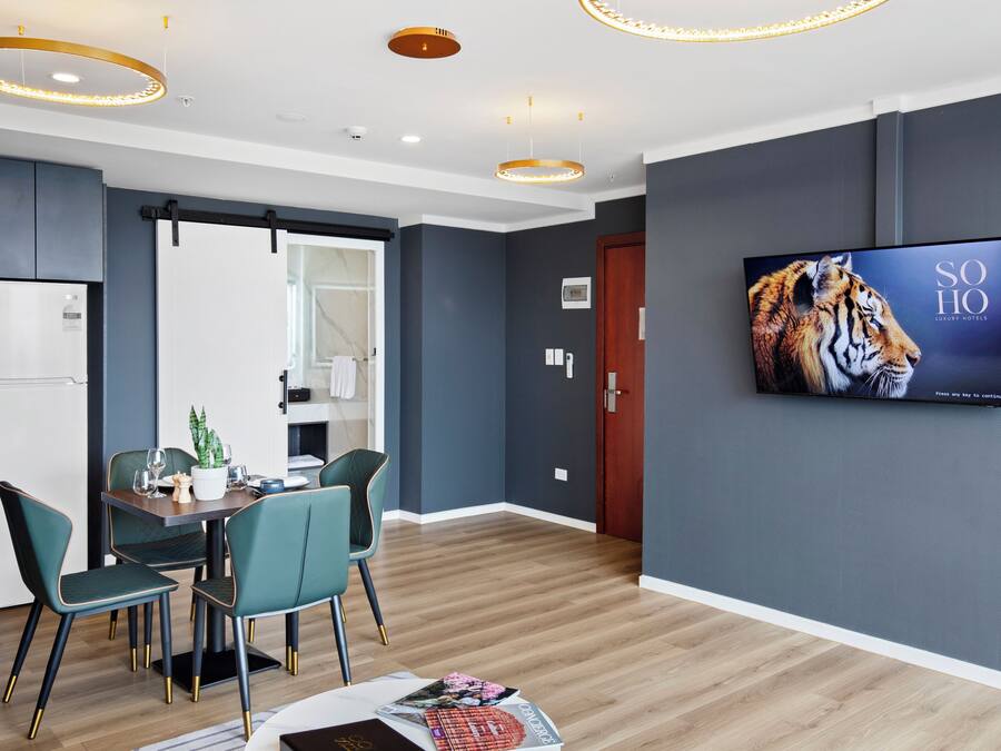 Una habitación de hotel moderna con zona de comedor, televisión de pantalla plana y suelo de madera.