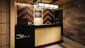 A reception desk with a modern design, featuring a wooden panel wall and a black counter. - Minn Nihonbashi (Tokyo)