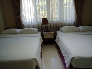 A hotel room with two beds, a nightstand, a lamp, and a window with sheer curtains. - An Hotel by Zuzu (Can Tho Municipality)
