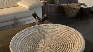 A cozy living room with a sofa, a woven basket, and a wood-burning stove. - Beautiful holiday home in the heart of Andalucia, A/C, Private Pool, WiFi. (Cómpeta)