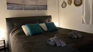 A neatly made bed with a dark headboard, teal and white pillows, and rolled towels on a textured bedspread. - Beautiful holiday home in the heart of Andalucia, A/C, Private Pool, WiFi. (Cómpeta)