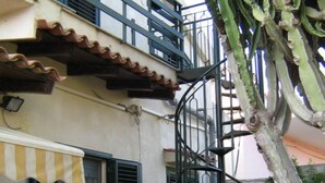 A building with a spiral staircase, a bench, and a tree.