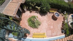 A rooftop garden with a circular seating area, a small water feature, and a staircase leading to the upper level.