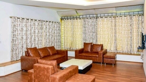 A living room with a brown sofa set, a coffee table, and a TV. - Surya Kiran Miramar (Panaji)