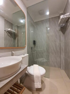 Ein modernes Badezimmer mit großem Spiegel, Waschbecken, Toilette und einer Duschkabine.