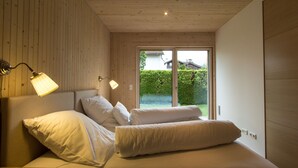 A bedroom with a wooden ceiling, a bed with white bedding, and two bedside lamps. - Exclusive Mondholz vacation apartment in a very quiet and central location in Garmisch (Garmisch-Partenkirchen)