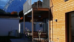A modern building with a wooden exterior, a balcony, and a view of mountains. - Exclusive Mondholz vacation apartment in a very quiet and central location in Garmisch (Garmisch-Partenkirchen)