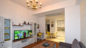 Una sala de estar moderna con un televisor de pantalla plana, una mesa de centro de madera y un sofá gris.