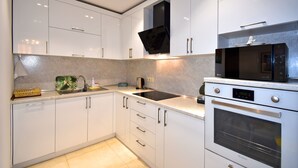 Una cocina moderna con armarios blancos, una campana extractora negra, un microondas y un horno.