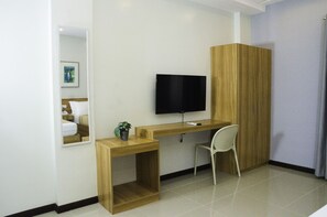 A room with a wooden desk, a chair, a television, and a wardrobe. - ELTI Suites (Angeles City)