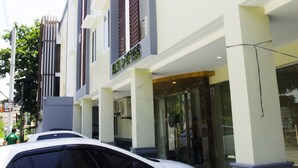 A modern building with a white facade, large windows, and a car parked in front. - ELTI Suites (Angeles City)
