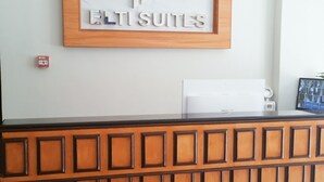 A reception desk with a framed logo, a fire alarm, and a security camera. - ELTI Suites (Angeles City)