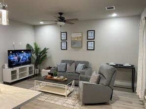 Relax in this stylish living room with a flat-screen TV, comfortable sofa, and armchair.