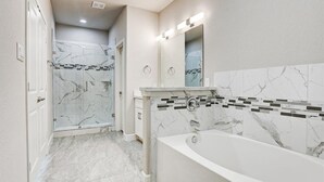 A modern bathroom with a marble floor, a glass-enclosed shower, and a freestanding bathtub. - Cozy home near Medical Center & NRG Stadium - B (Houston)