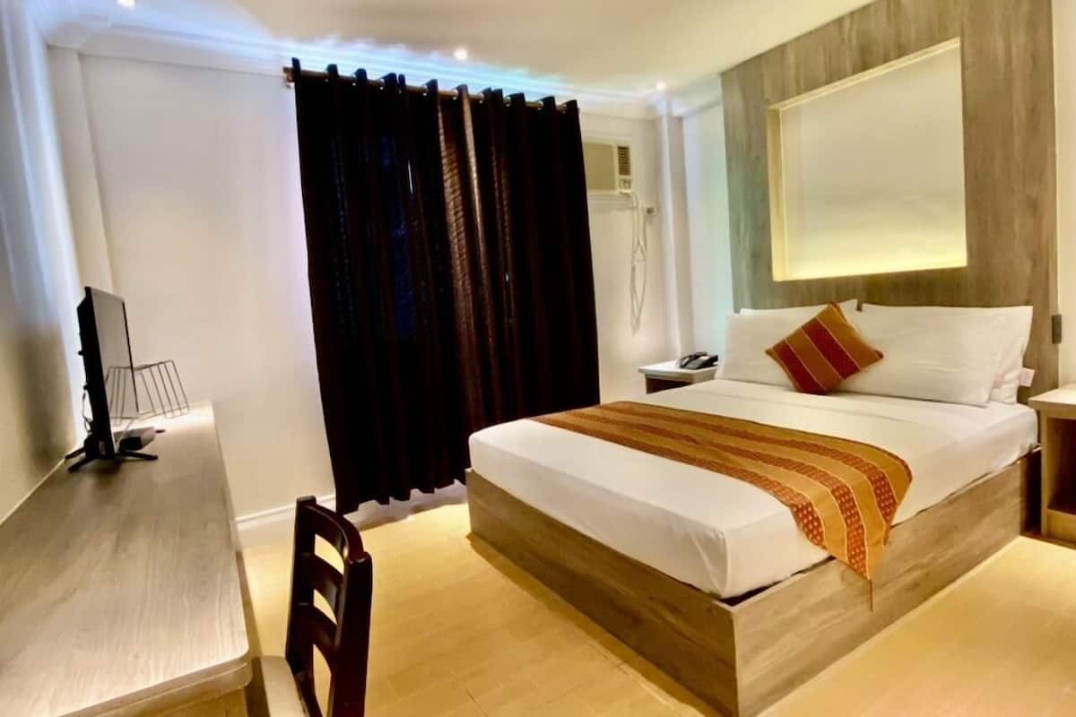 A hotel room with a bed, a desk, and a chair.