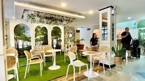 A modern hotel lobby with a green artificial turf area, white furniture, and a decorative ceiling. - HOTEL EUROASIA (Angeles City)