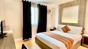 A modern hotel room with a large bed, a desk, and a chair. - HOTEL EUROASIA (Angeles City)